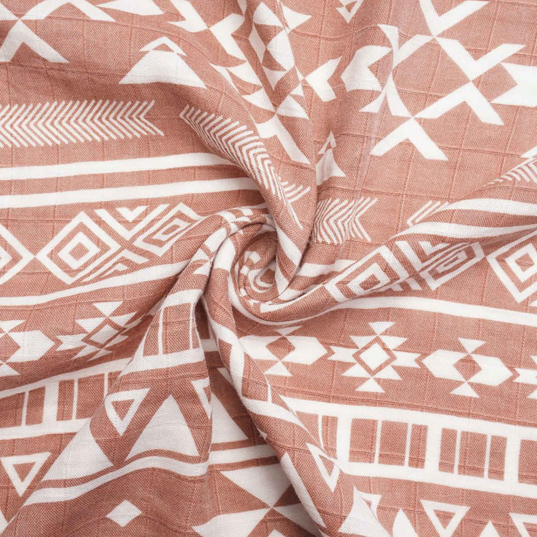 Close-up texture of breathable bamboo-cotton muslin fabric with artisan-inspired white tribal motifs on terracotta background – stylish, gender-neutral baby blanket ideal for organic baby gifts, newborn comfort, and inclusion in curated baby gift boxes.