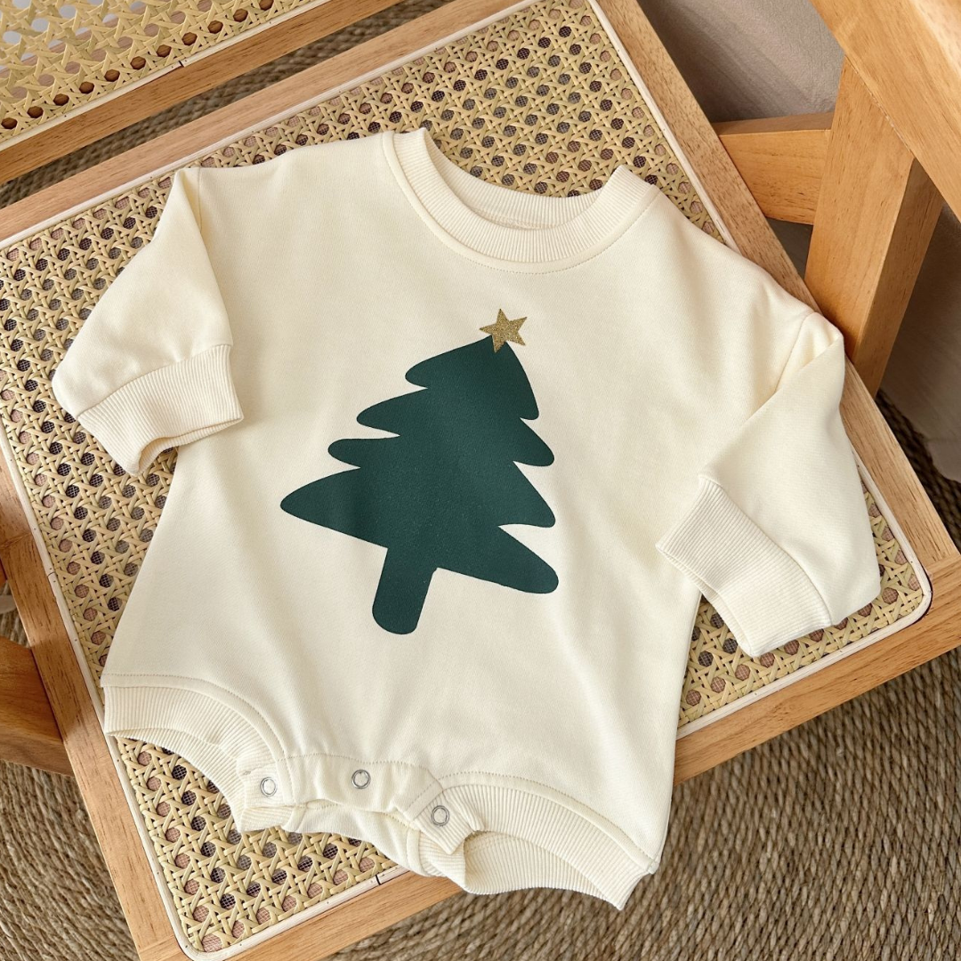 Baby onesie with green tree design on a wooden surface