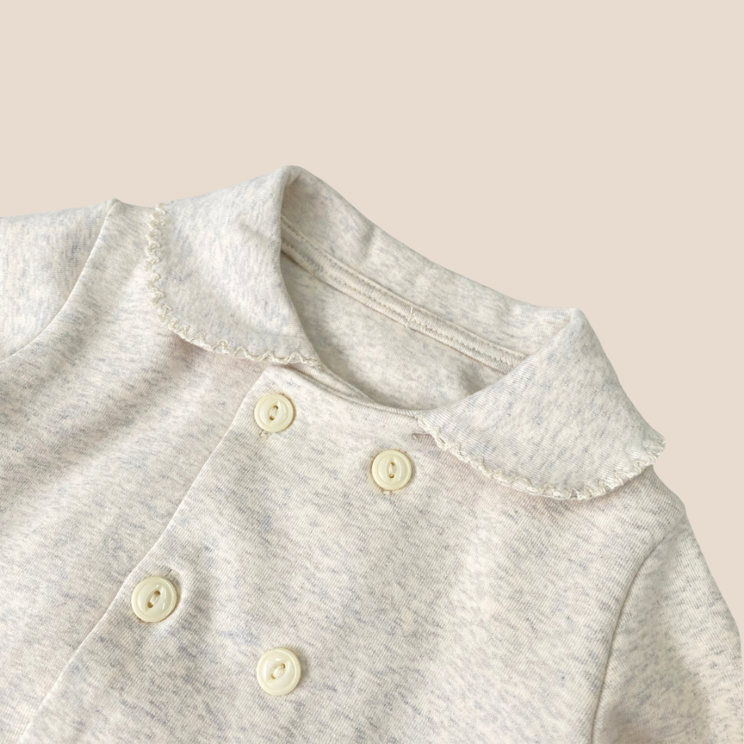 Close-up of a gray shirt with button details on a beige background