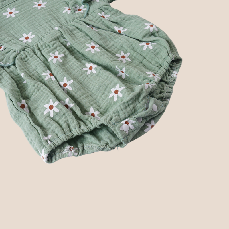 Bottom detail of sage green muslin baby romper with snap buttons