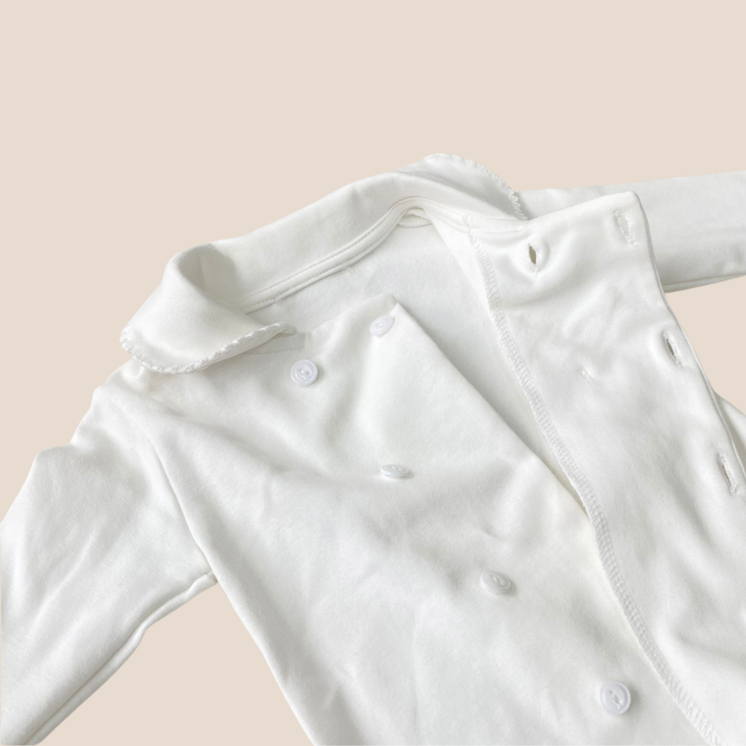 White baby onesie on a beige background