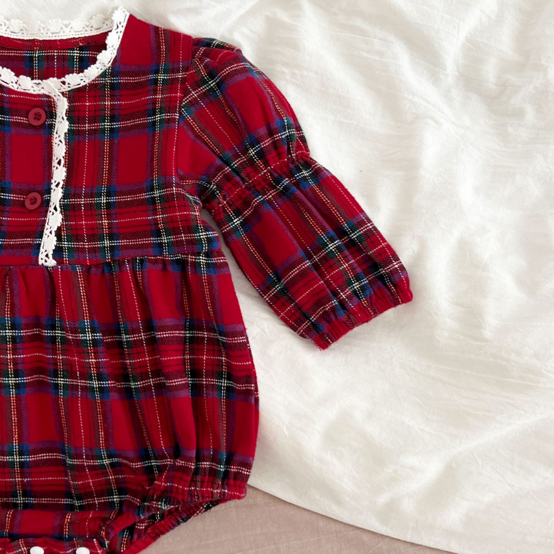 Red plaid baby dress with lace trim on a white surface