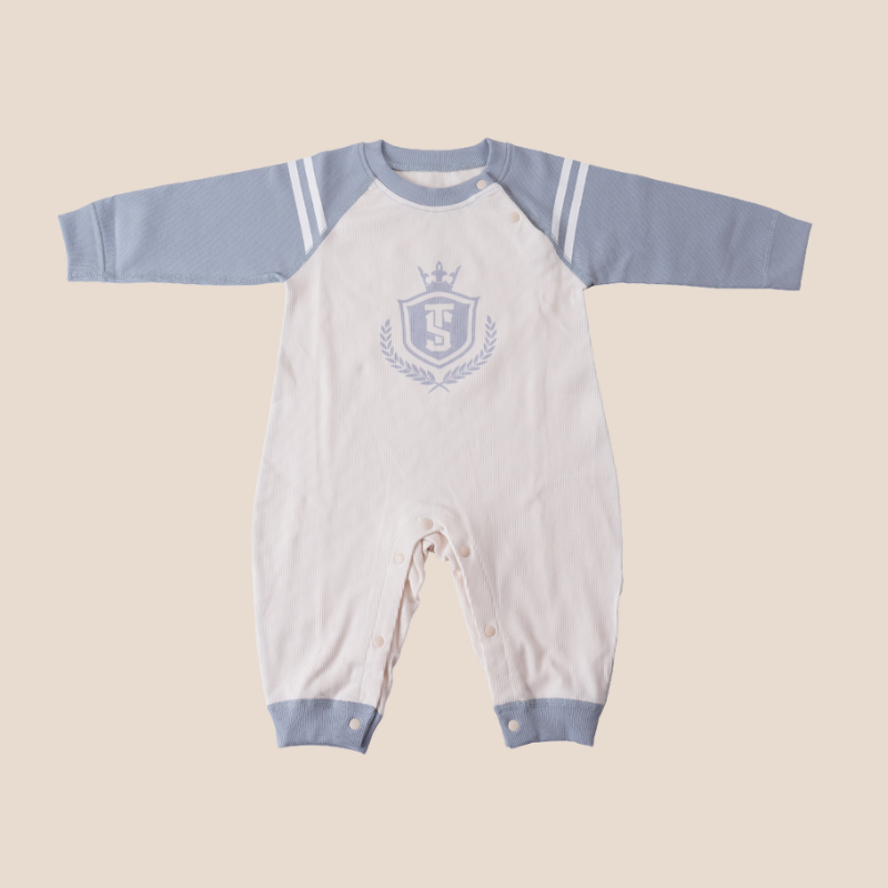 Long sleeve baby romper in cream with printed crest and blue sleeves