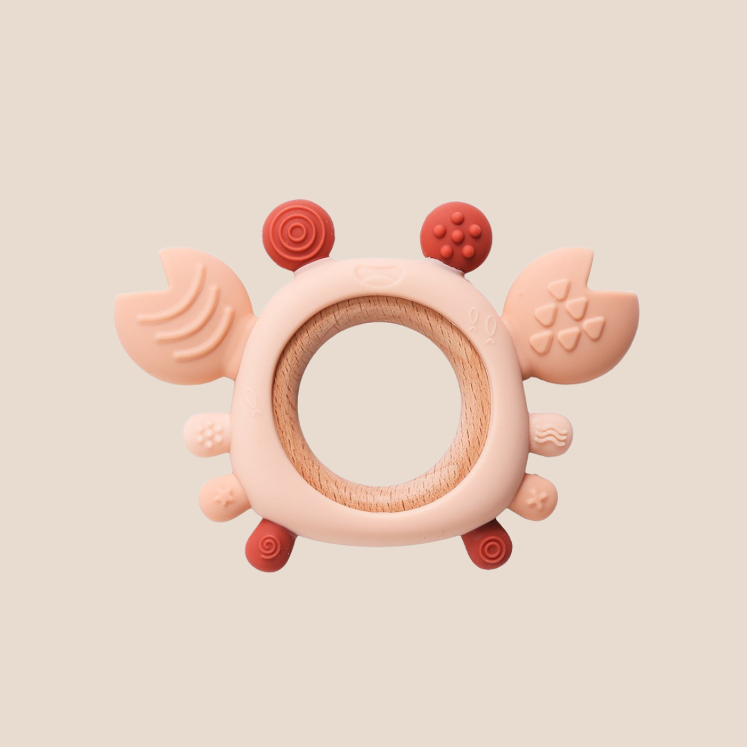 Pink and red baby teething ring on a beige background