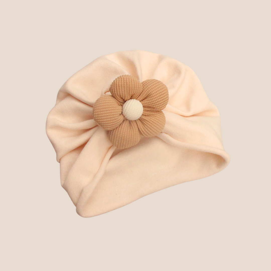 Beige baby turban with a brown flower accessory on a beige background