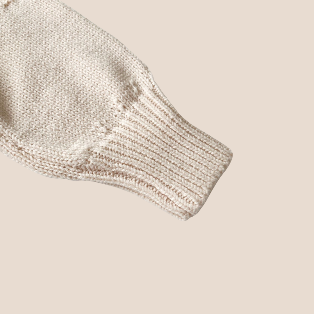 Close-up of a textured beige baby sweater on a beige background