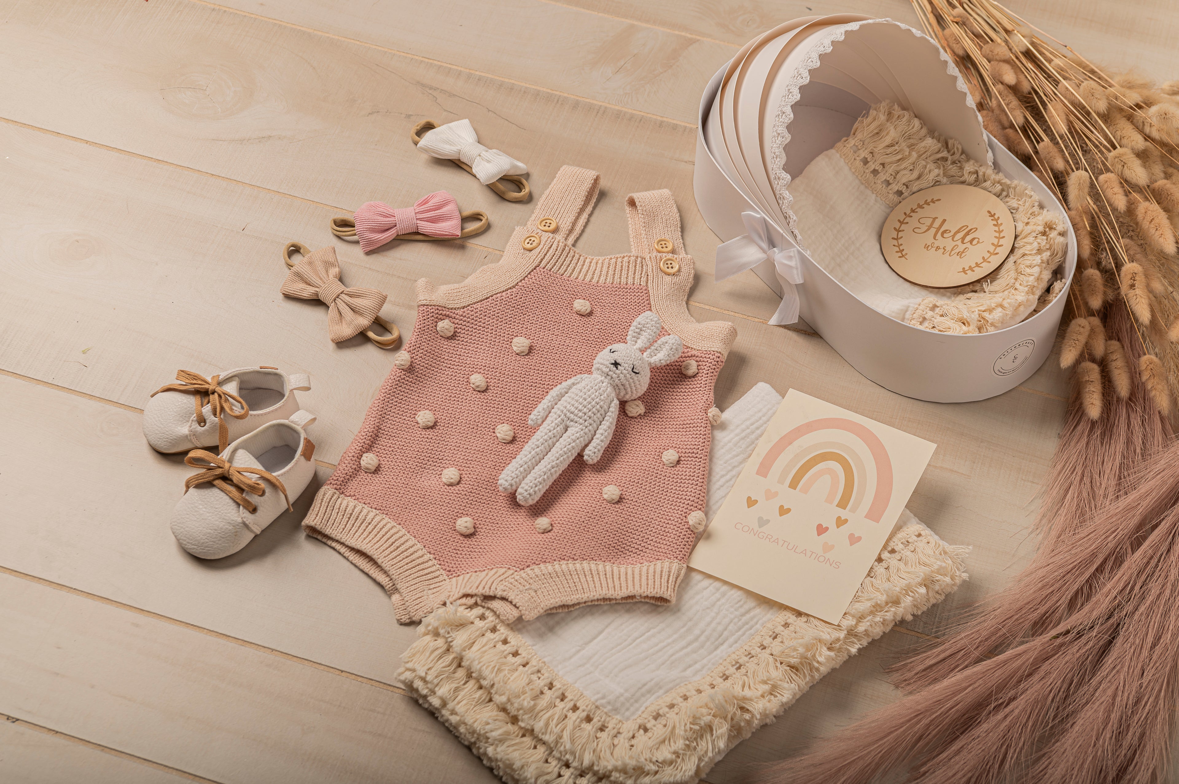 Build-your-own baby gift box featuring a pink polka dot romper, crochet bunny toy, newborn shoes, pastel bows, and congratulatory card. Luxury newborn gift idea for girl. Ideal for baby showers, newborn photoshoots, or personalized keepsake gifting.
