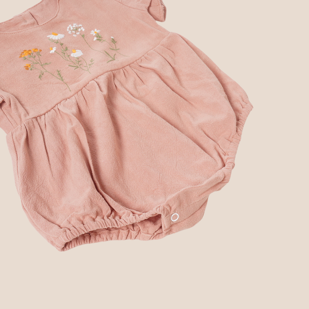 CLOSE UP BOTTOM VIEW of embroidered baby romper in soft pink – ideal for baby shower presents and personalized client gifting