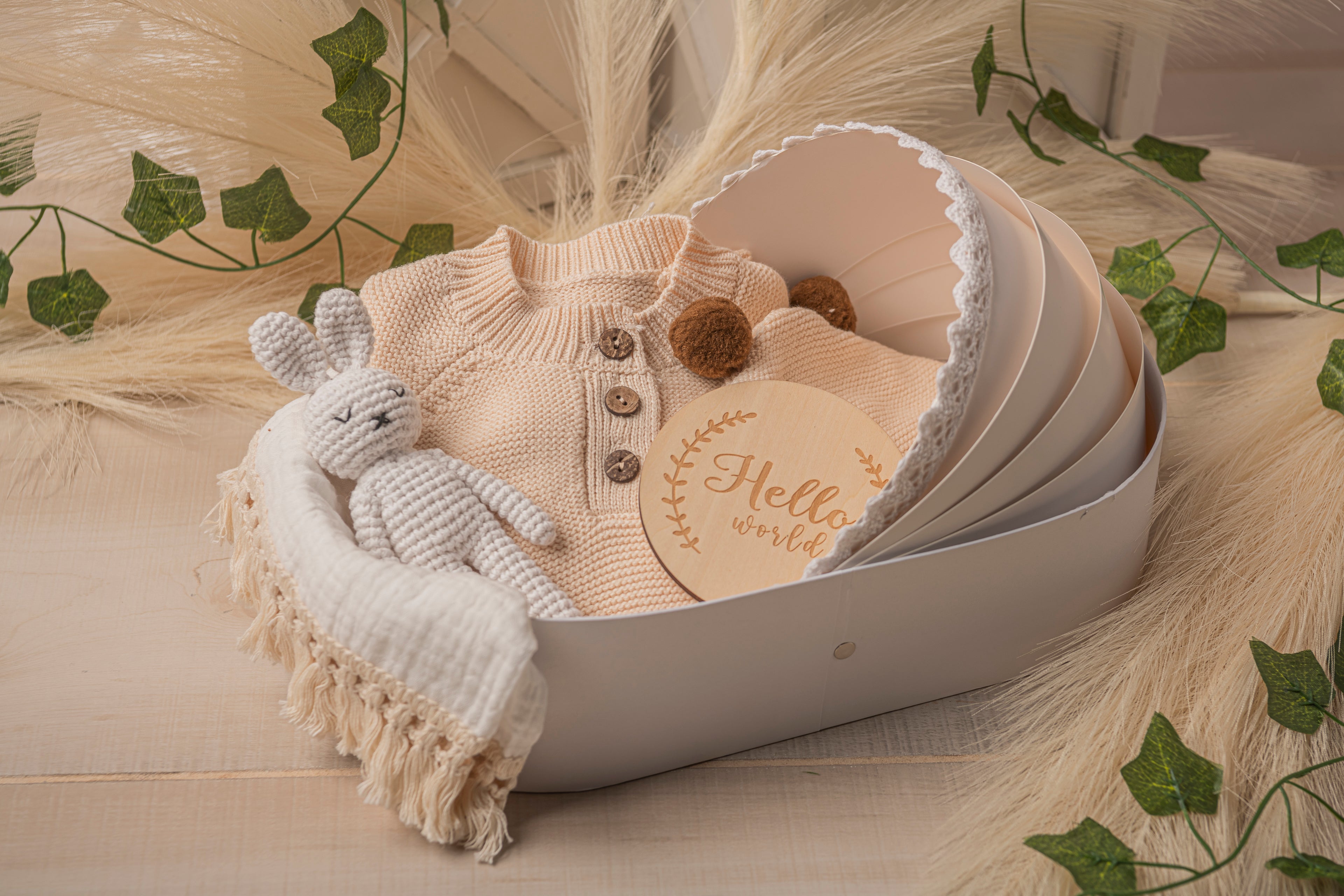 Eco-conscious baby gift box featuring handcrafted essentials: ivory knit romper, muslin swaddle, bunny comforter, soft-sole shoes, and bear knit hat. Elegant, plastic-free baby shower gift idea for minimalist or nature-inspired nursery themes.