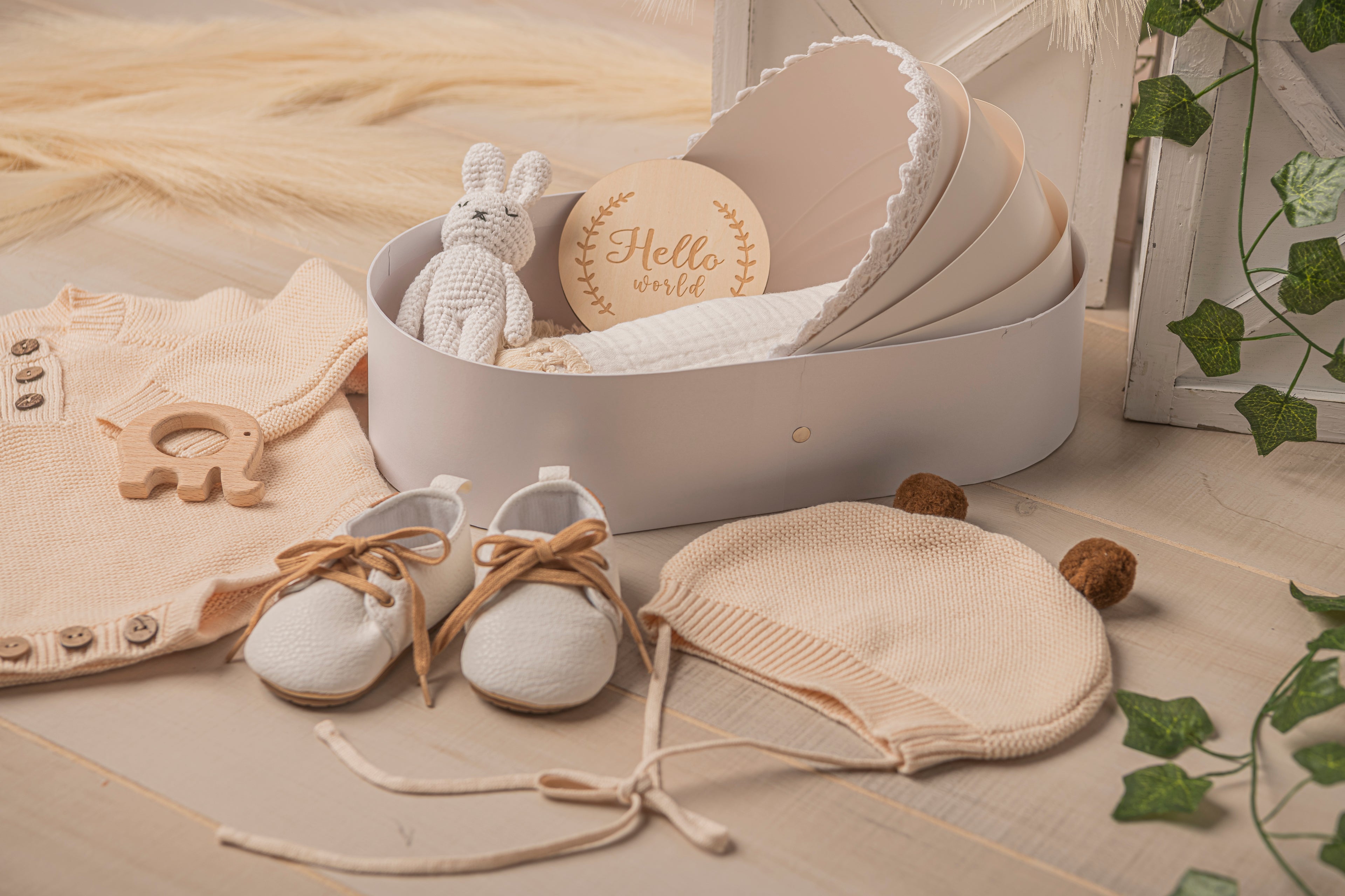 Complete baby gift basket set for newborns featuring neutral tones: soft romper, handmade baby shoes, bunny plush toy, and cozy knit blanket in a white keepsake box. Thoughtful gift for expecting parents, baby registry, or baby shower. Side View