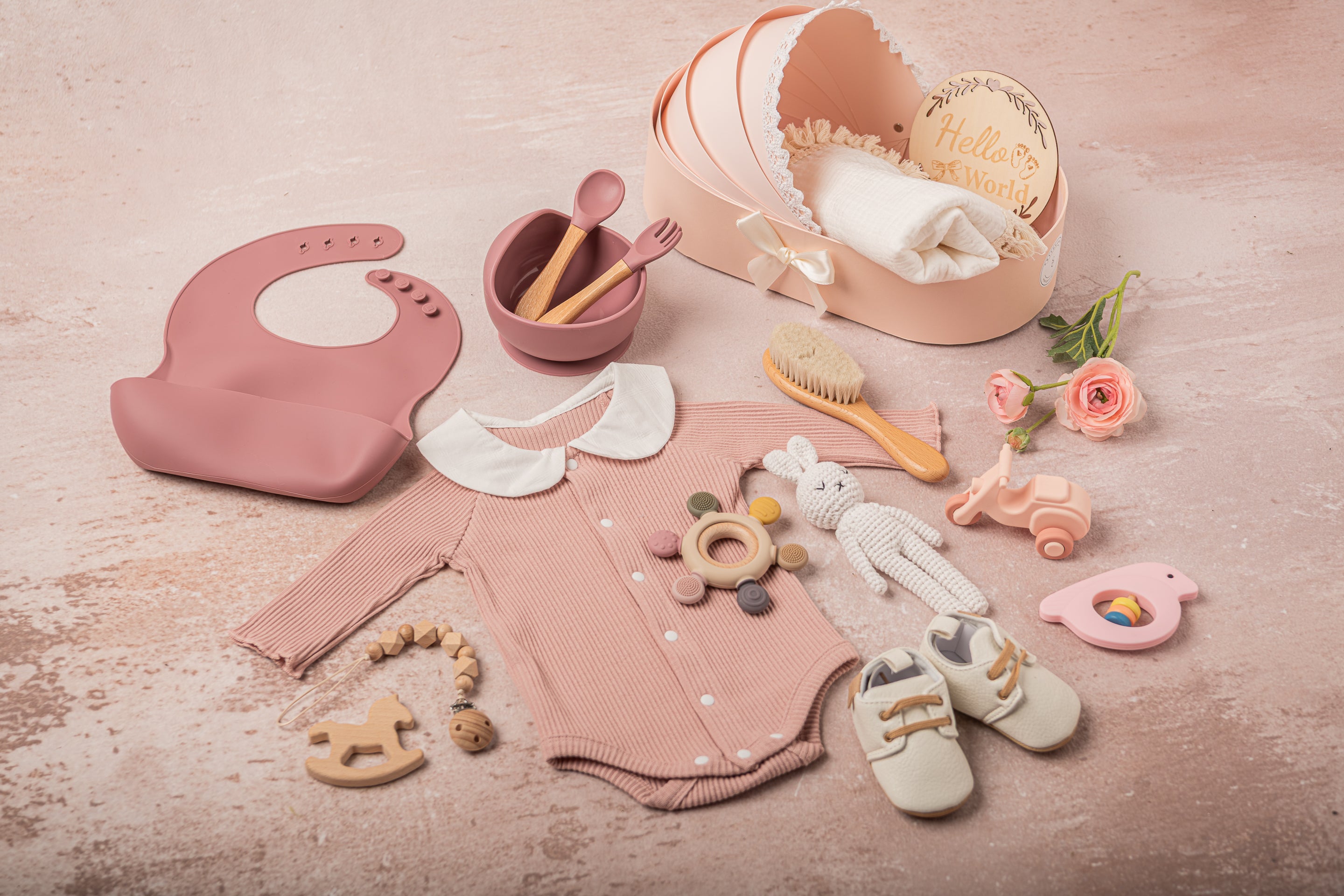 Exquisite baby girl gift set in soft pink and white, featuring 100% cotton outfits, a fringed swaddle, leather baby shoes, handmade bunny plush, and sustainable wooden and silicone toys, elegantly arranged for a luxury gifting experience- side view
