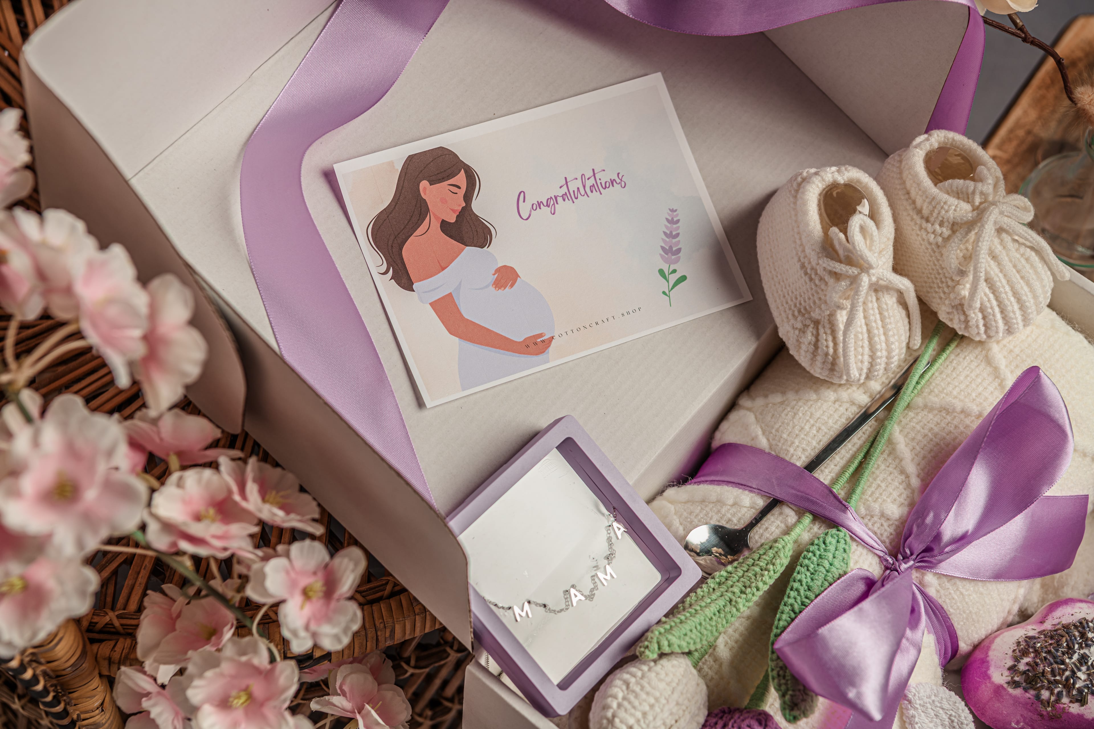 Baby shower gift set with baby booties, card, and necklace in a box.