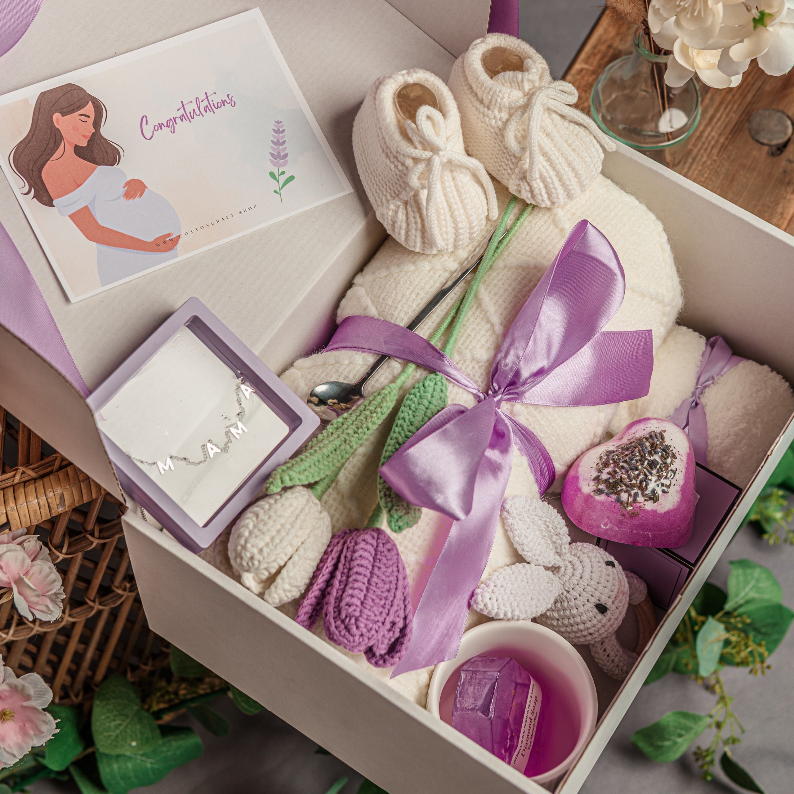 Gift box with baby booties, socks, and jewelry on a decorative background.
Lavender luxury baby shower gift basket for mom and newborn