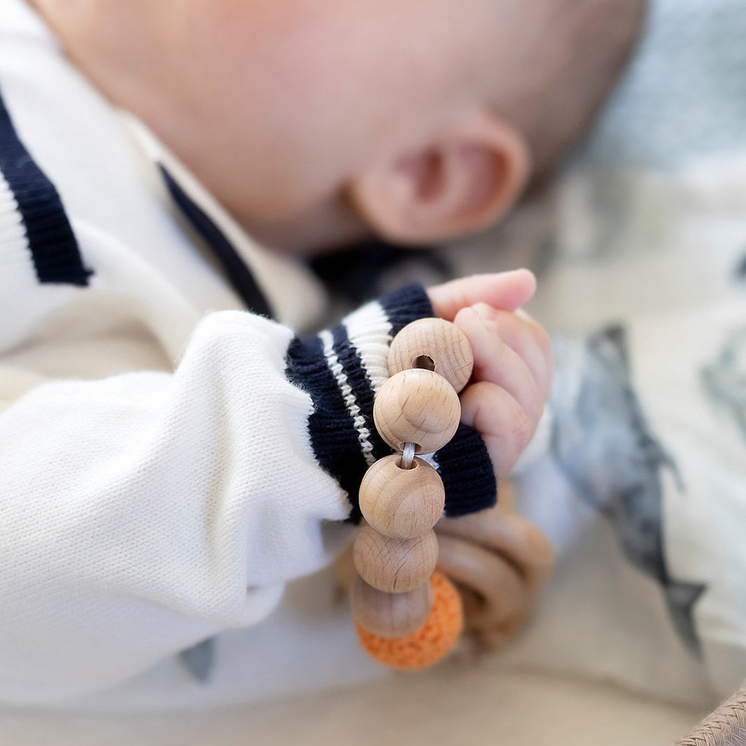 Baby wearing a wooden teething ring with colorful beads
