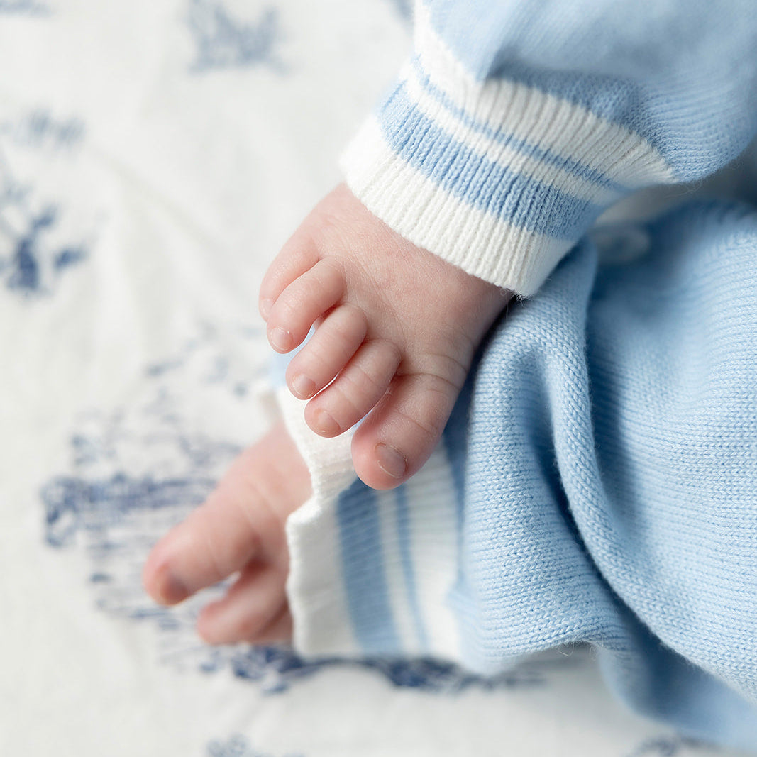 Close-up of baby feet in blue and white striped socks on a soft surface