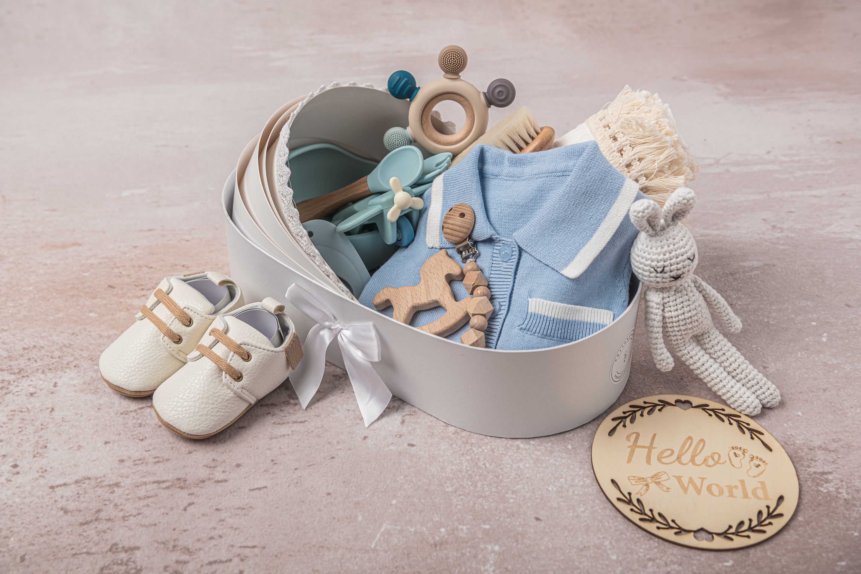 Premium baby boy gift set in classic blue and white tones, including soft 100% cotton outfits, a breathable fringed swaddle, leather shoes, a knitted bunny plush, and eco-friendly silicone and wooden toys—the ultimate newborn gift.