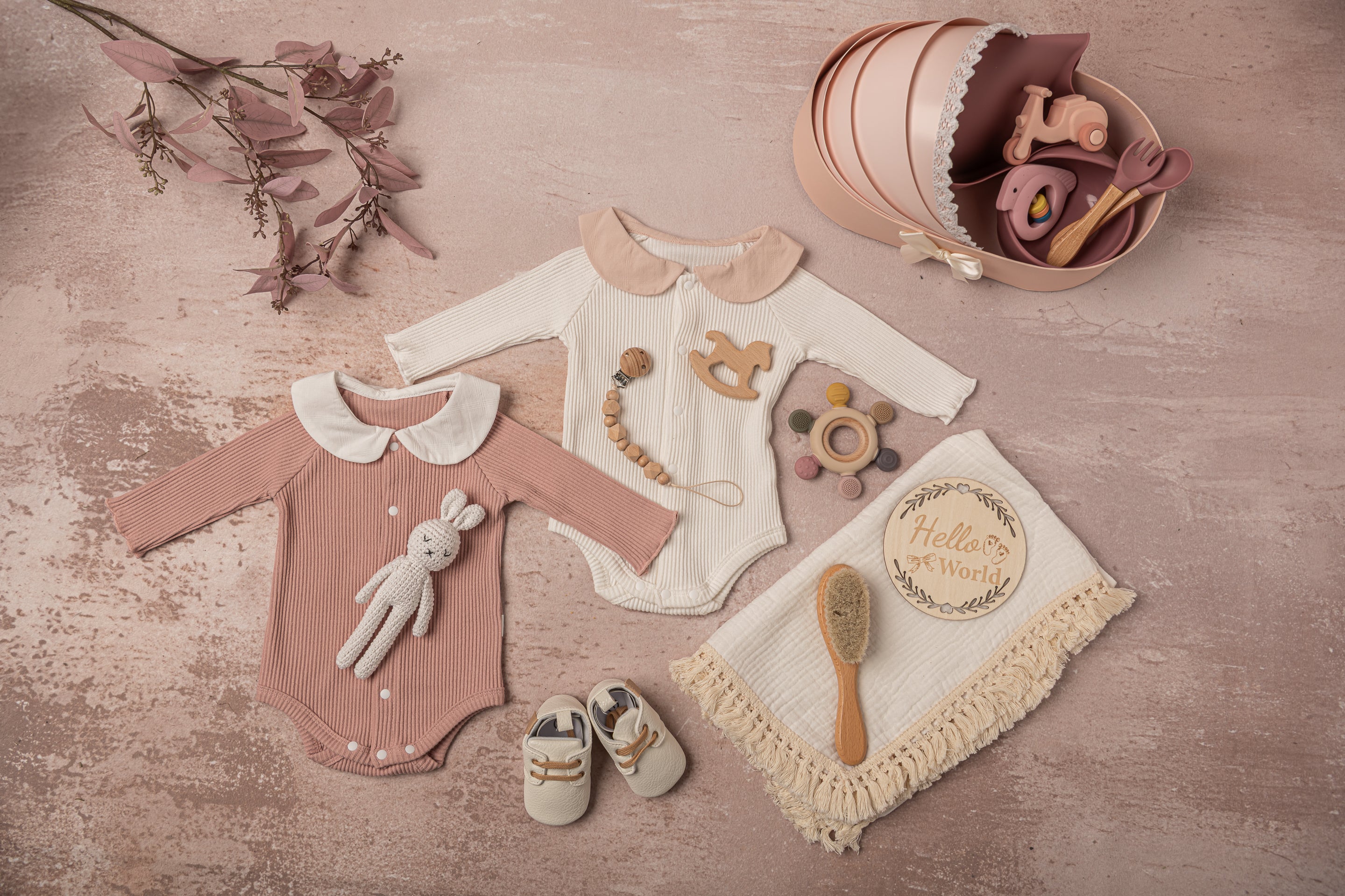 Luxury baby girl gift set in soft pink and white, featuring premium cotton outfits, a fringed swaddle, handcrafted leather baby shoes, hand-knitted bunny plush, and eco-friendly wooden and silicone teething toys—a perfect baby shower gift.