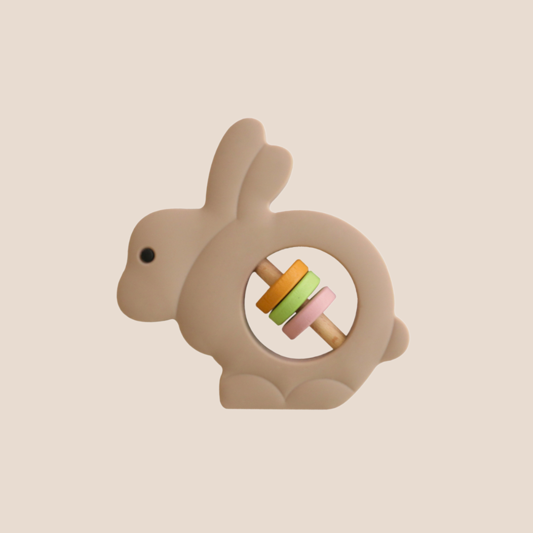 Bunny-shaped teething ring with colorful beads on a beige background