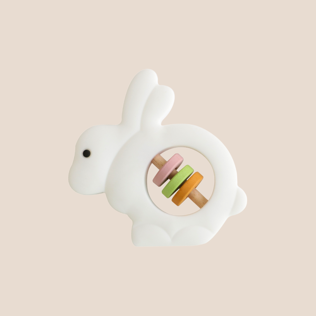 White rabbit-shaped toy with colorful buttons on a beige background