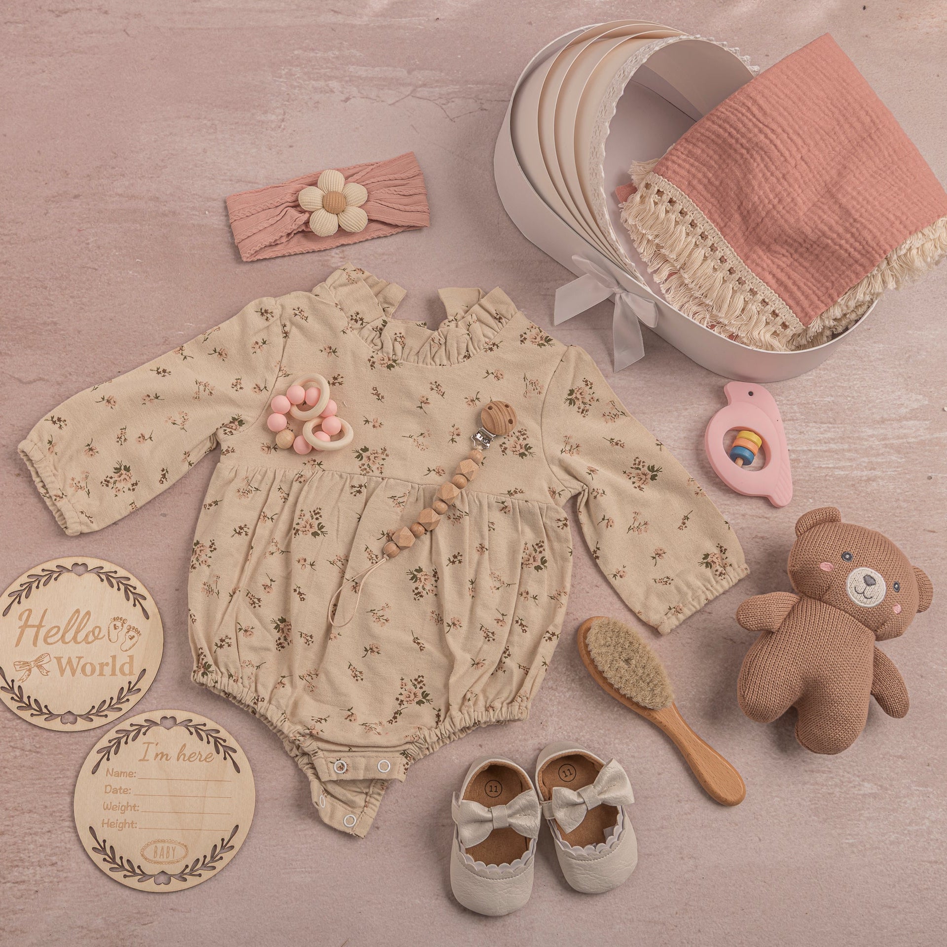 Baby clothing set with romper, shoes, headband, and toys on a wooden surface