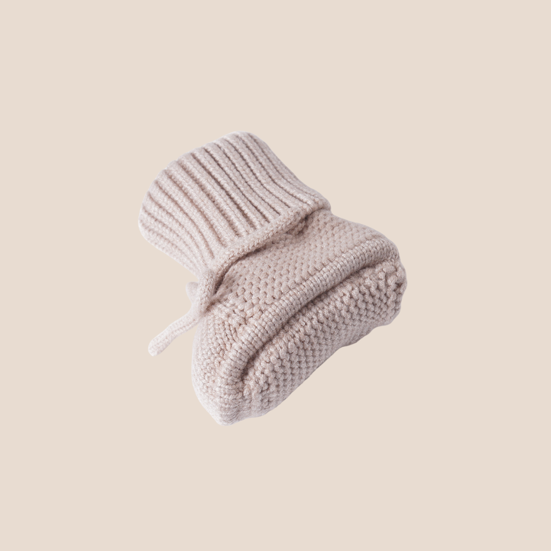 Bottom view of beige baby booties highlighting hand-knitted sole – perfect soft sole design for newborns in custom baby gift boxes and client appreciation sets.