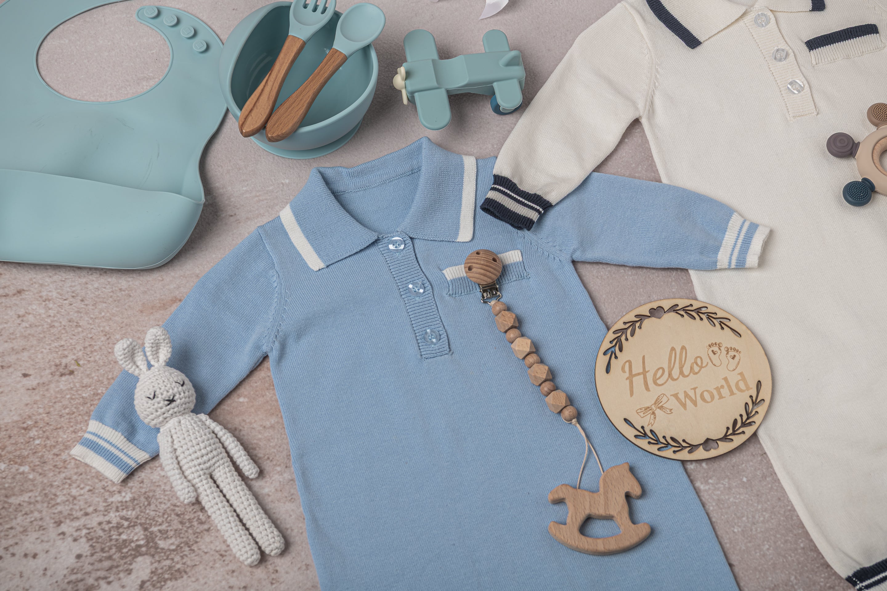 Premium baby boy gift set in classic blue and white tones, including soft 100% cotton outfits, a breathable fringed swaddle, leather shoes, a knitted bunny plush, and eco-friendly silicone and wooden toys