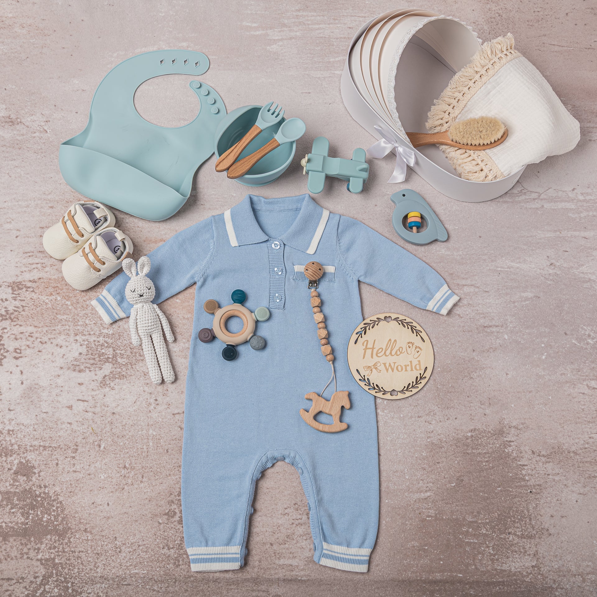 Premium baby boy gift set in blue and white, featuring 100% cotton outfits, a breathable swaddle, soft leather shoes, a hand-knitted bunny plush, wooden horse teether, and BPA-free silicone teething toys—ideal for high-end baby gifting.