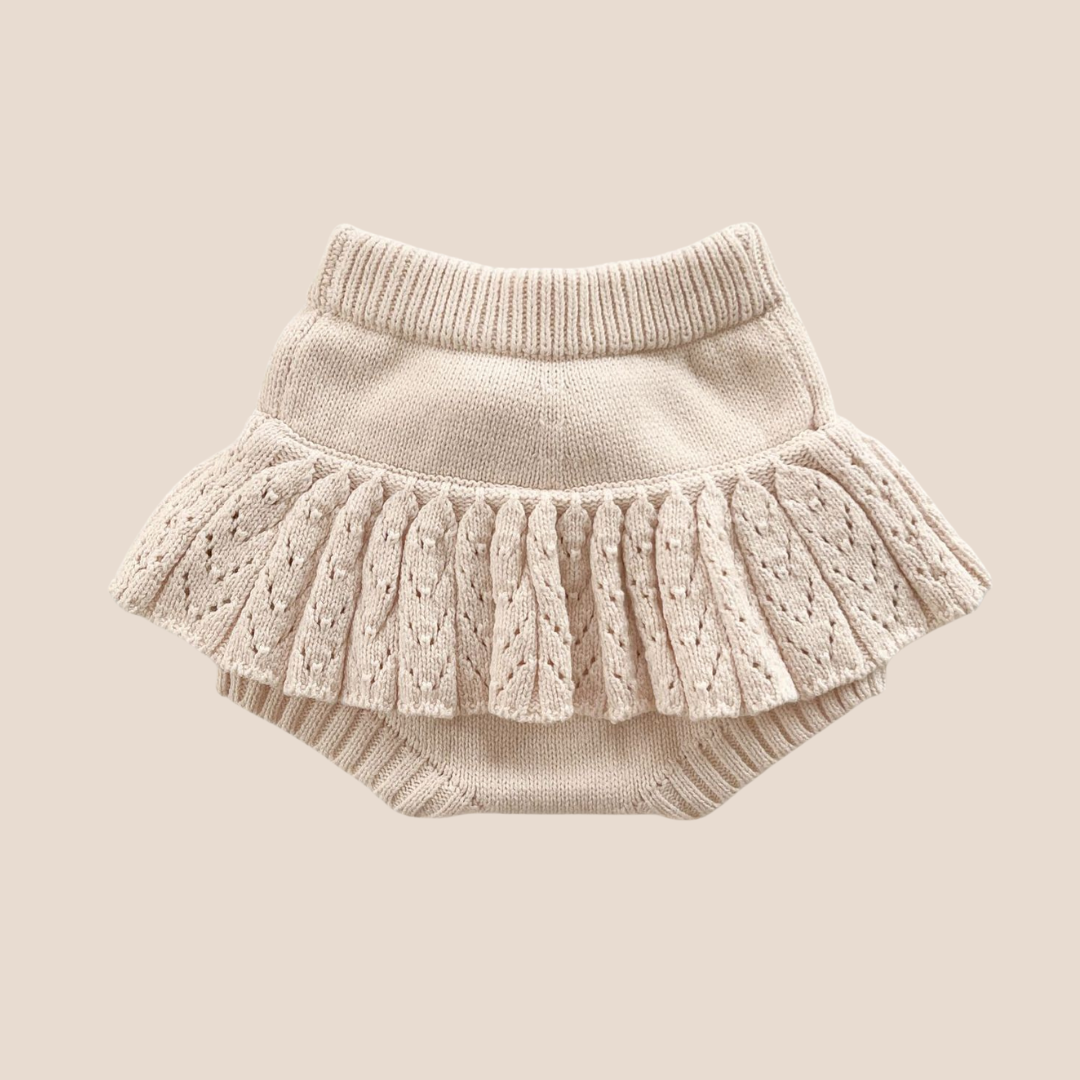 Knitted baby skirt with ruffled layers on a beige background
