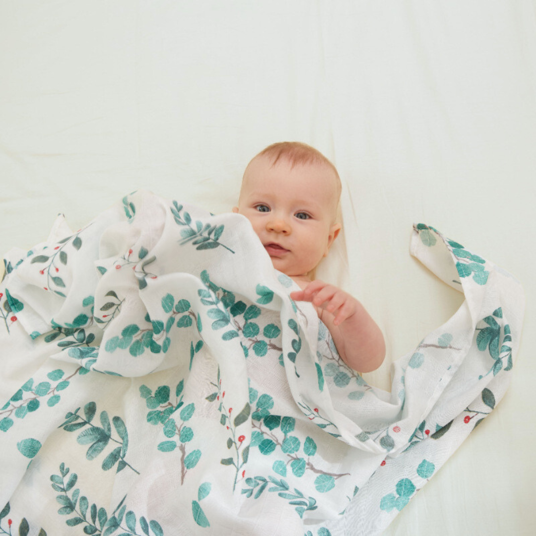 Adorable baby wrapped in eucalyptus print bamboo cotton swaddle blanket – a soft, breathable, eco-friendly newborn essential ideal for customized baby shower gifts, modern baby hampers, and new mom gifting.