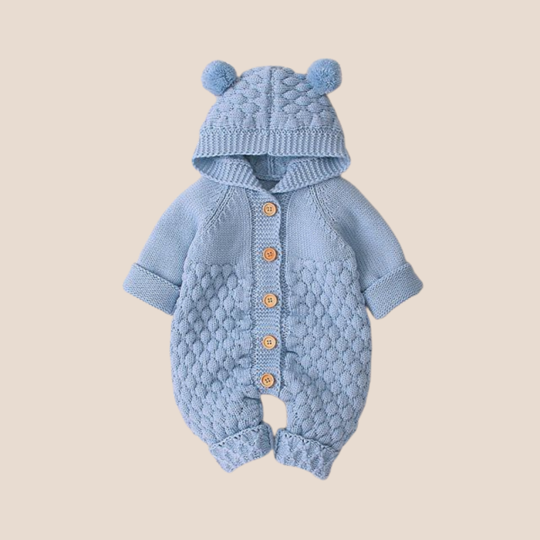 Blue knitted baby romper with hood on a beige background