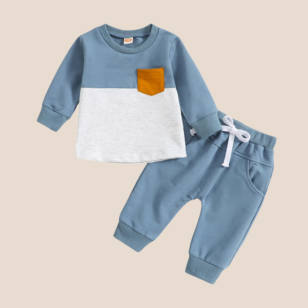 Children's blue and white long-sleeve shirt with a brown pocket and matching pants on a beige background