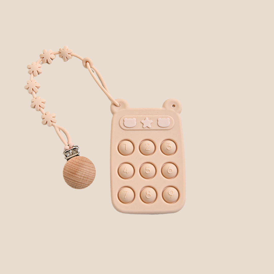 Pink silicone teething toy with buttons and a pacifier clip on a beige background