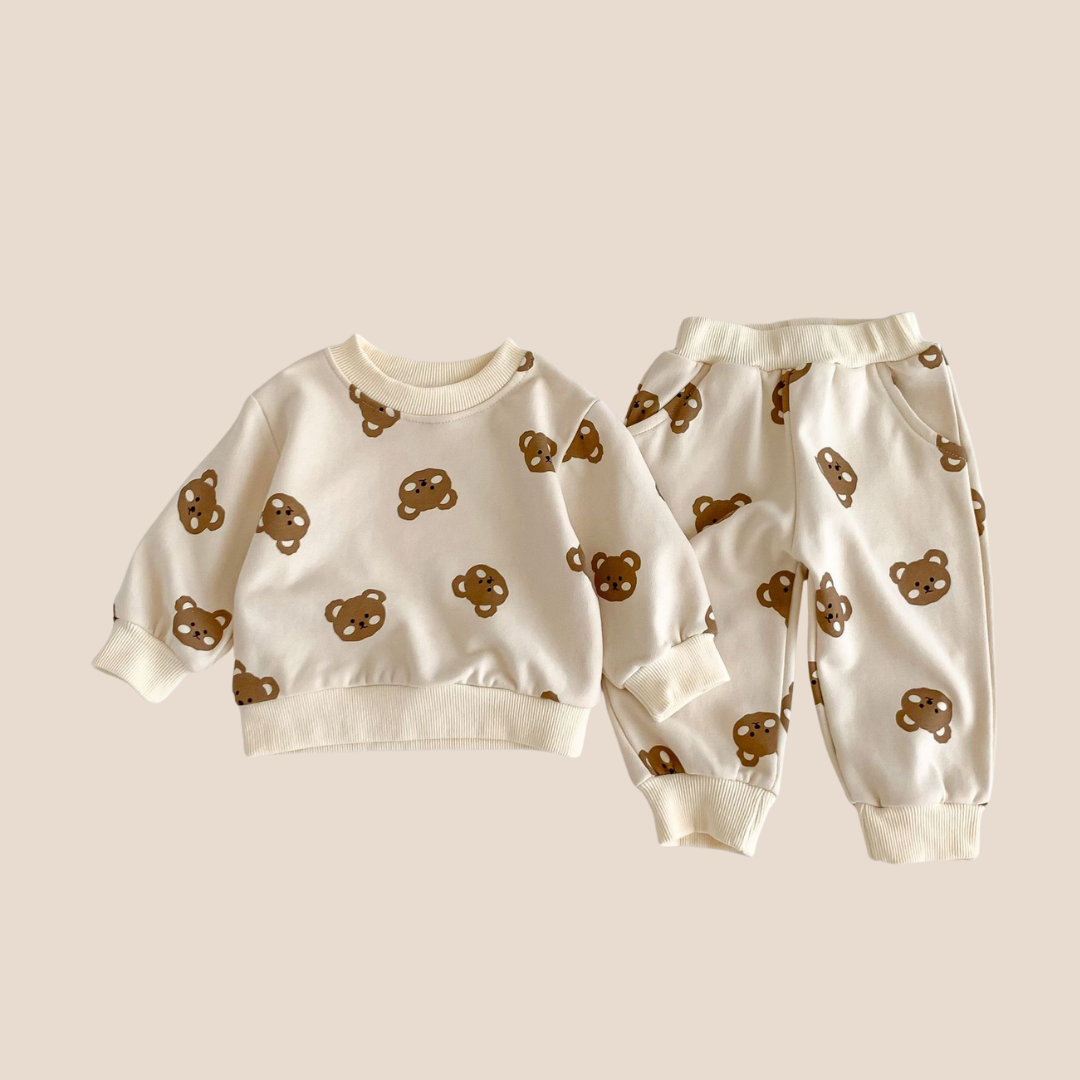 Children's sweatshirt and pants set with bear patterns on a beige background.Teddy Bear baby loungewear set for 0–6 months – unisex cotton baby outfit with cream sweatshirt and joggers, perfect for baby shower gifts, custom baby gift boxes, and cozy new baby clothing.
