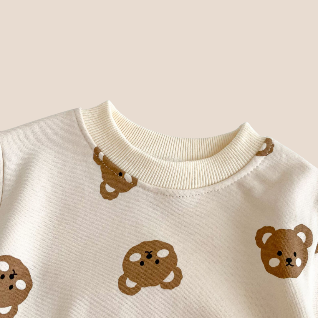 White sweater with brown bear illustrations on a beige background