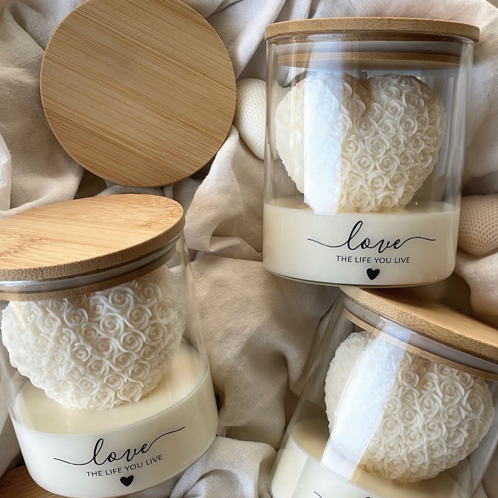 Decorative ivory heart candle crafted from natural soy wax with intricate rose detailing, presented in a reusable glass container with bamboo lid for a modern minimalist aesthetic.