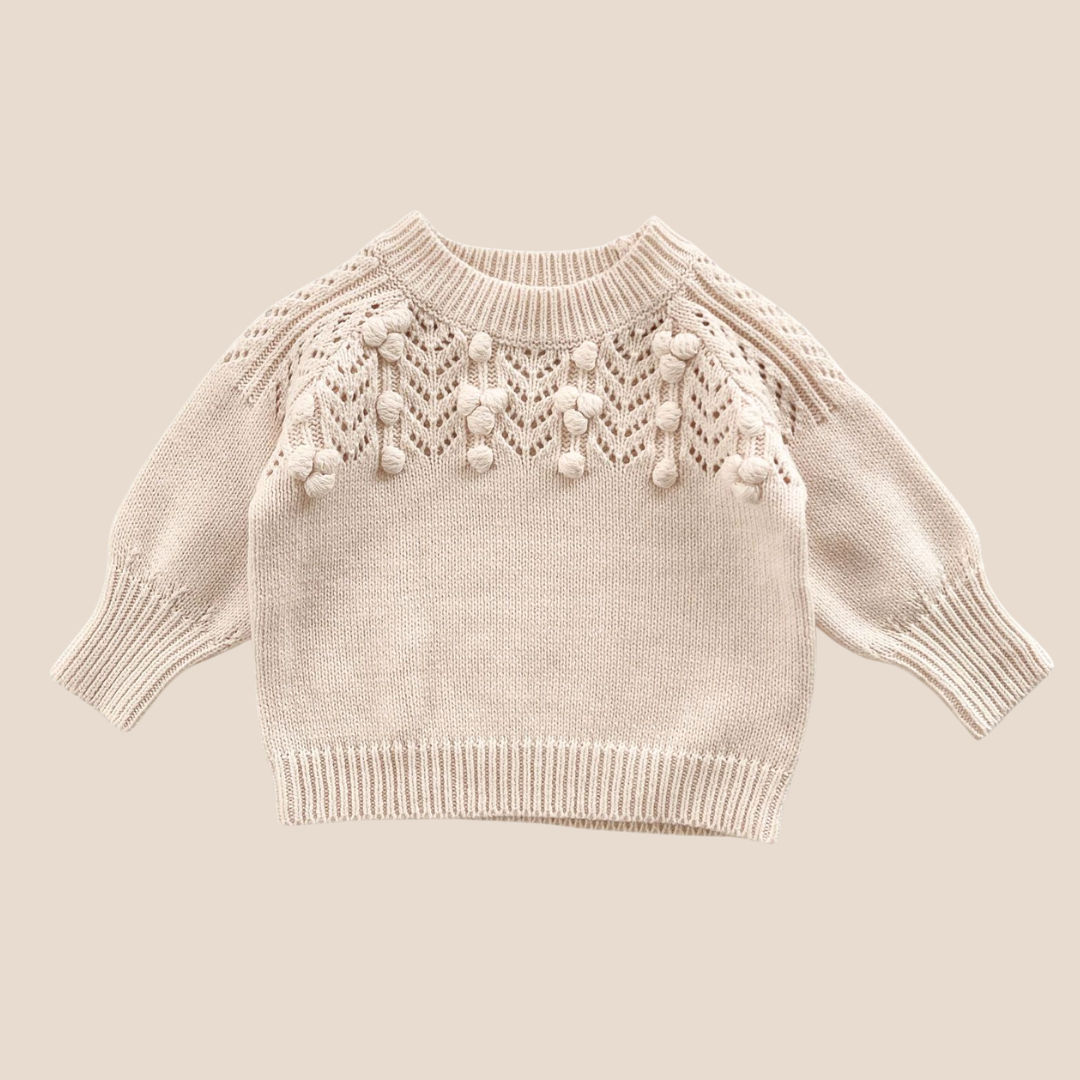 Beige knitted sweater with decorative elements on a beige background