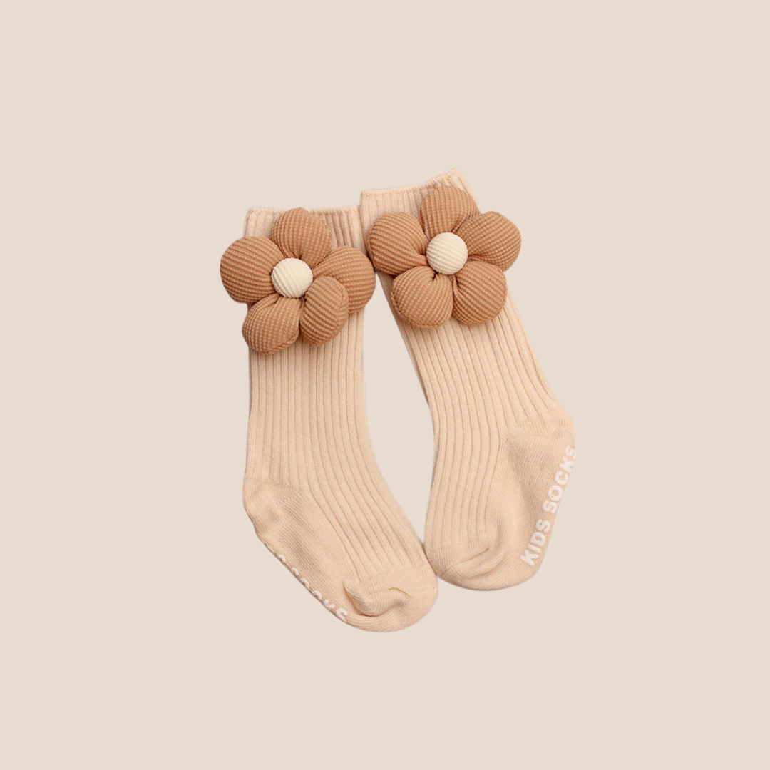 Beige baby socks with brown flower designs on a beige background
