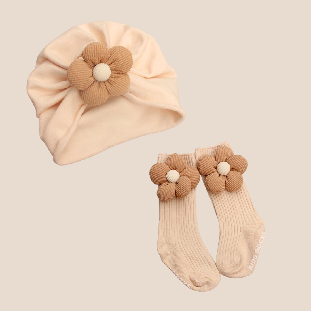 Baby hat and socks set with flower details on a beige background