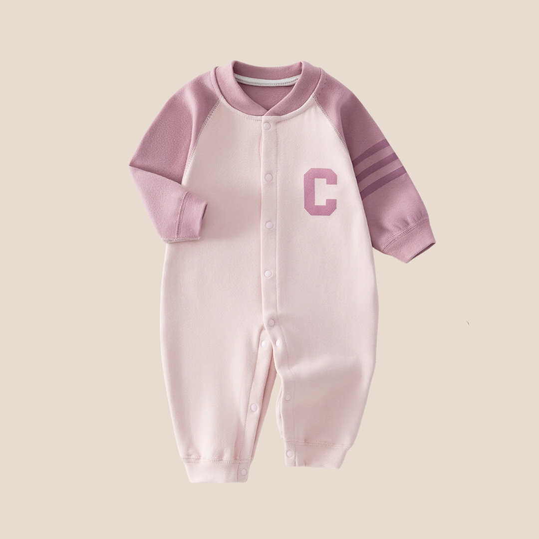 Cotton Craft Varsity C colorblock baby romper in blush pink with sporty striped sleeve and snap closure.