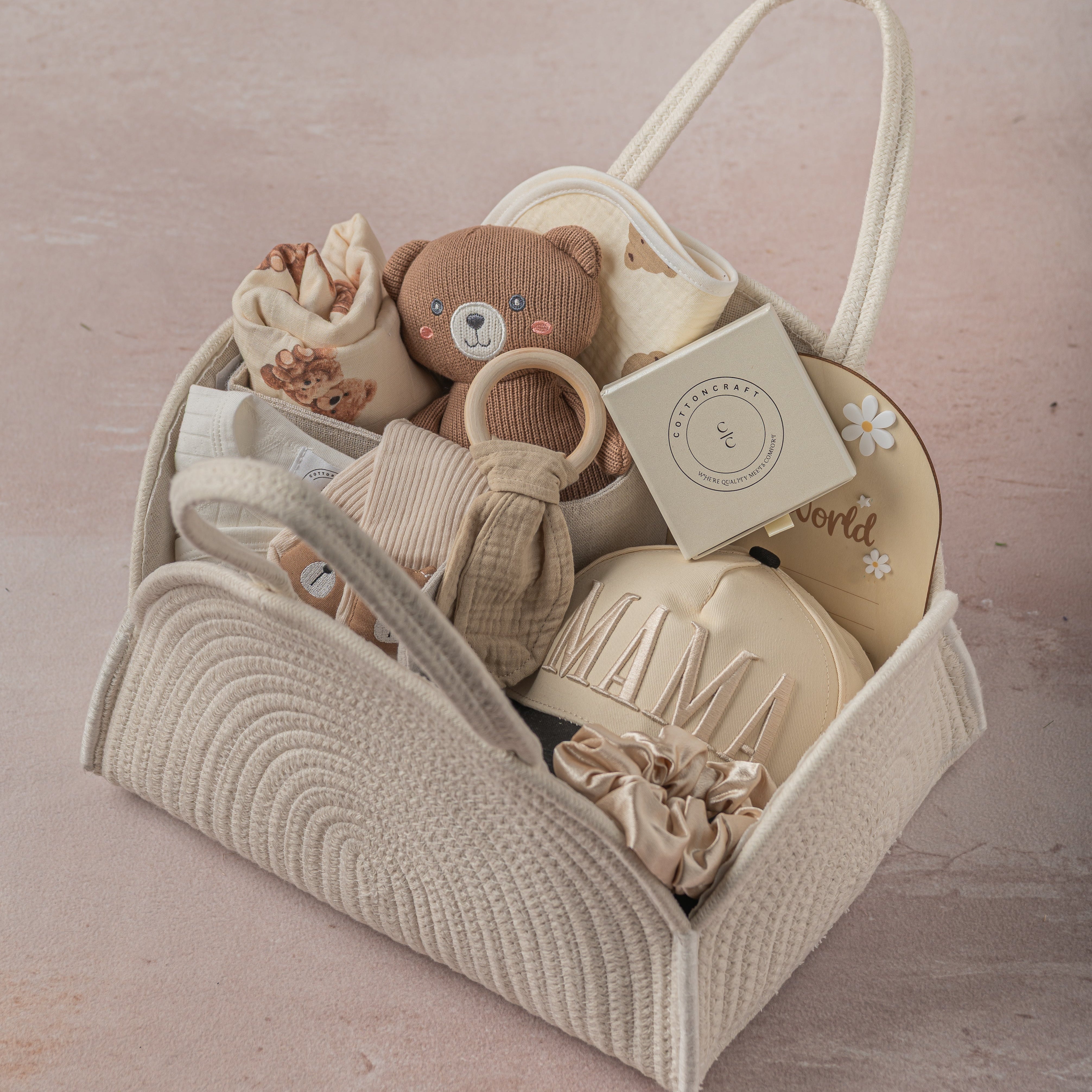 Baby toy set in a woven basket on a soft pink background