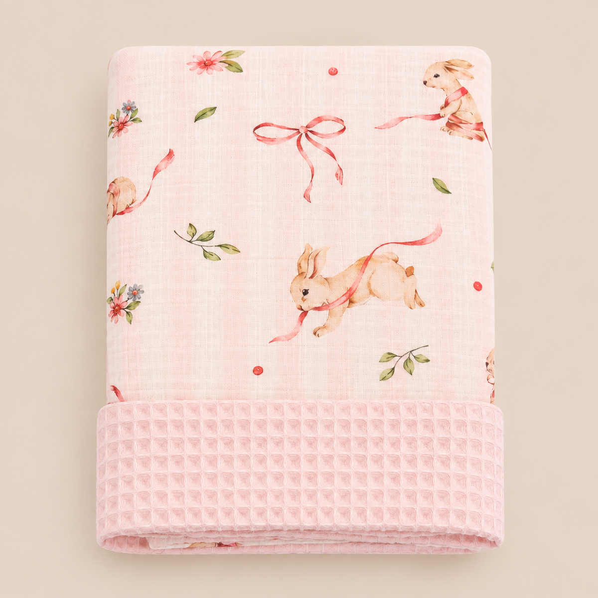 Folded Blossom Bunny baby blanket showing soft pink waffle texture and delicate watercolor rabbit print.
