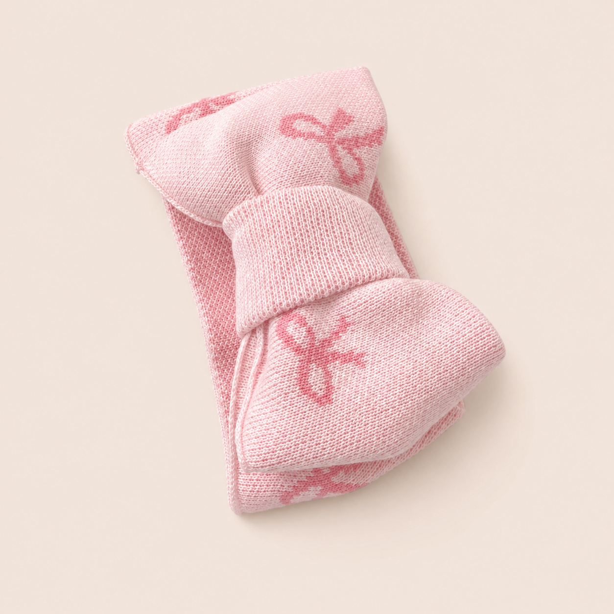 Close-up of the matching pink knit bow headband crafted from soft worsted cotton.
