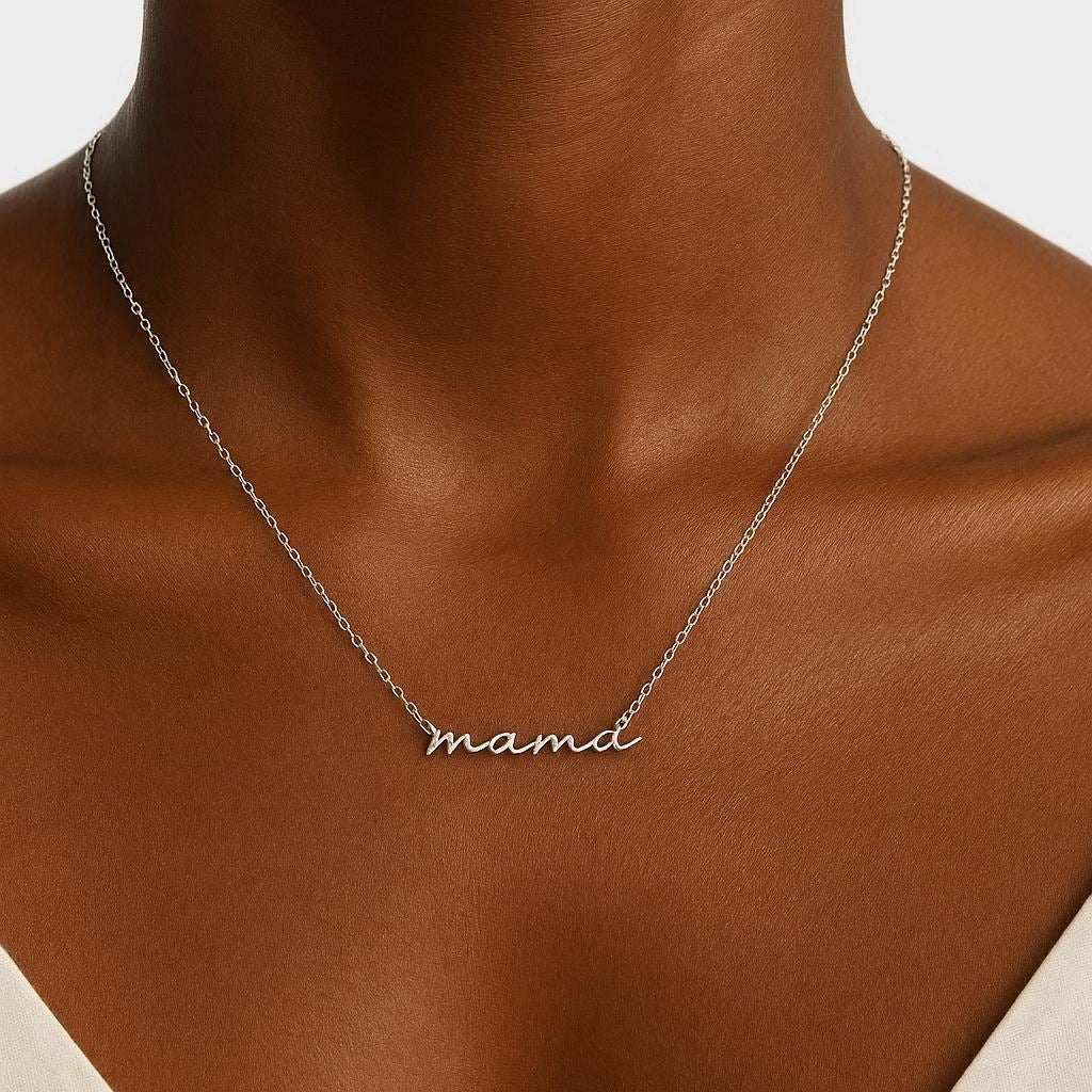 Silver necklace with 'mama' pendant on a person's neck against a neutral background