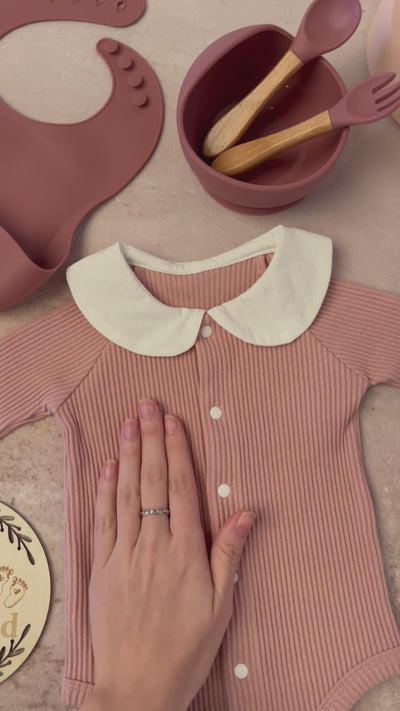 Luxury baby girl gift set featuring soft pink and white 100% cotton outfits, a fringed swaddle, leather baby shoes, hand-knitted bunny plush, and sustainable wooden and silicone toys, elegantly displayed. Video clip showing details of baby items 